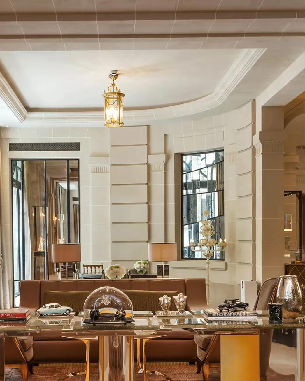 Luxury suite with tall windows, dark wood desk, pale ceiling, and gilt accents