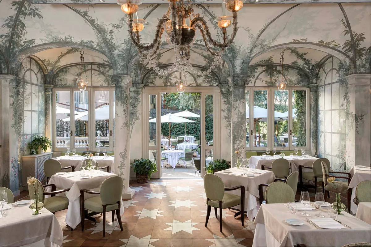 Elegant dining gallery with arched niches, columns, and fireplace beyond