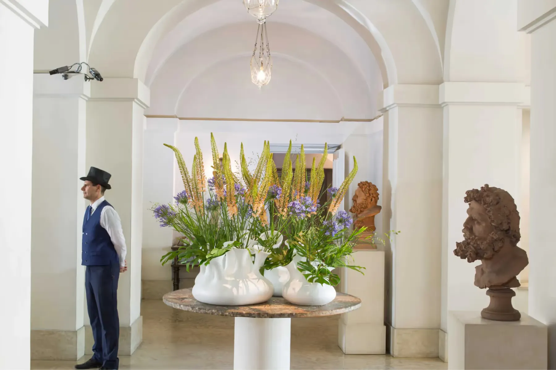 Entrance hall with arched ceiling, tall arrangement of yellow and green flowers in pedestal vase