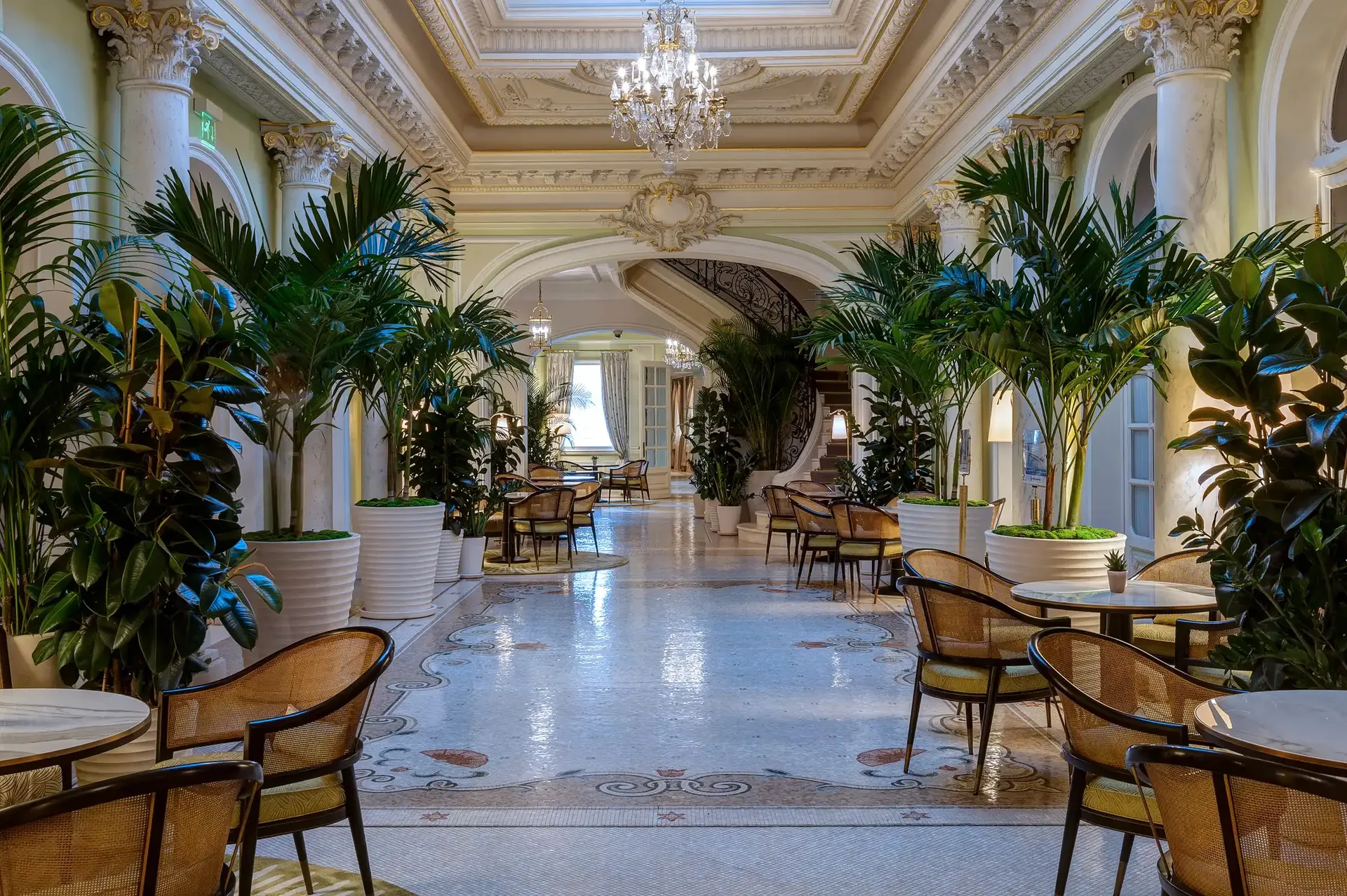 Grand hallway with coffered ceiling, crystal chandelier, palm trees and marble flooring
