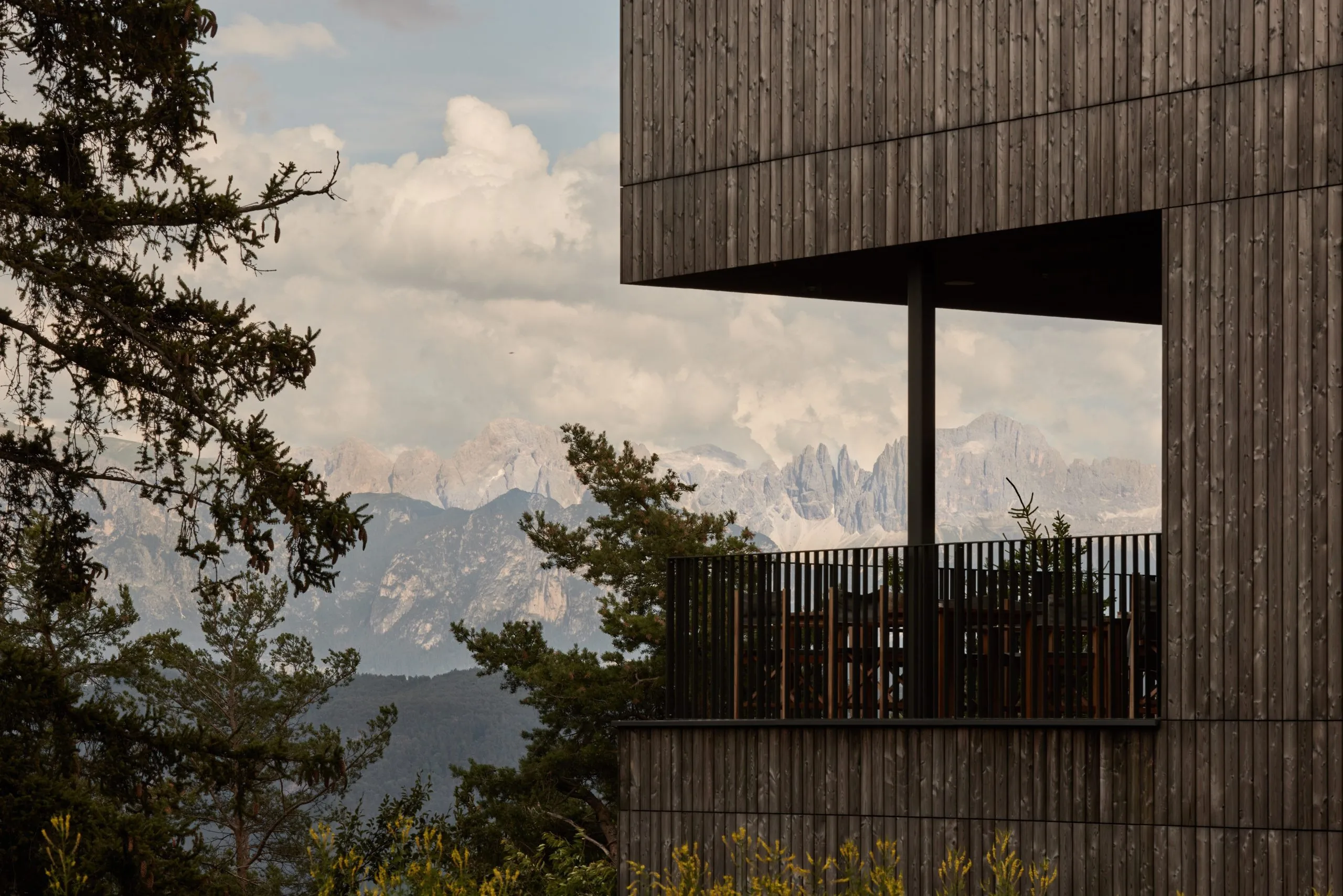 Cantilevered wooden balcony overlooking Dolomite mountain peaks under dramatic sky