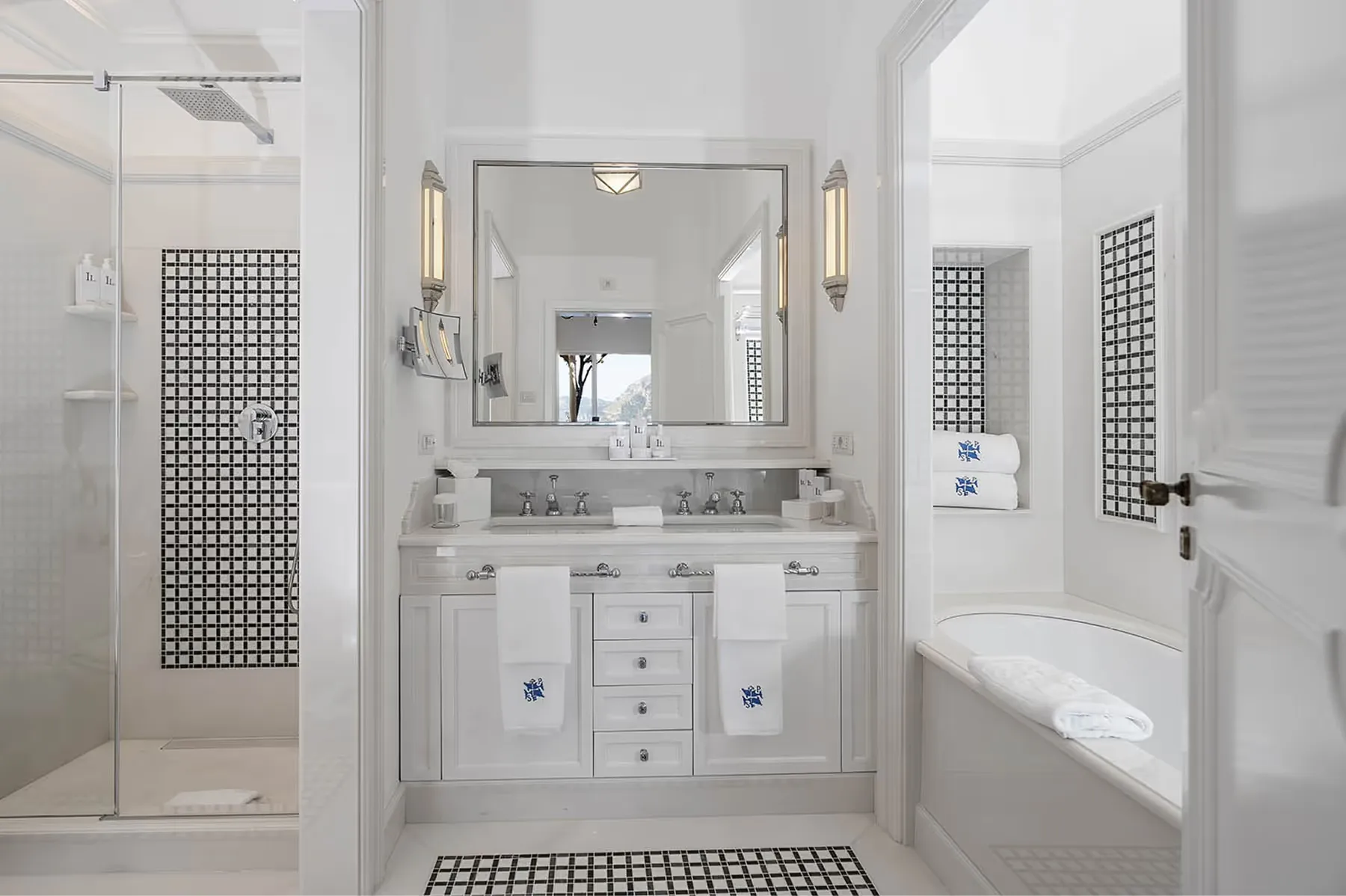 Neutral-toned bathroom with marble vanity, large mirror, brass sconces, and spa-like finishes