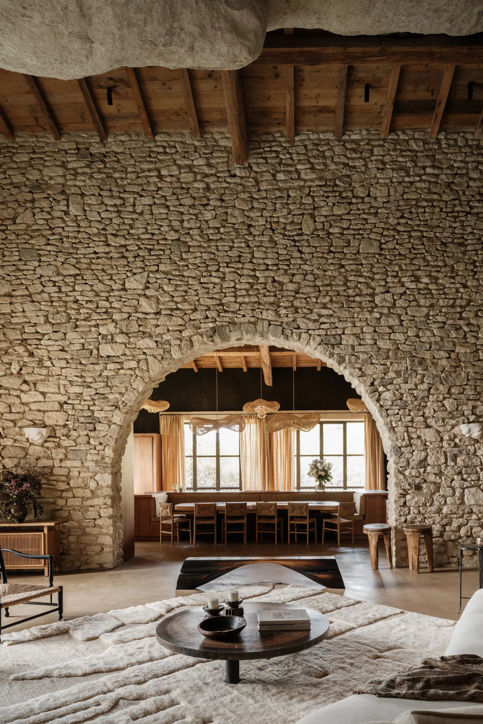 Stone archway with wooden lintels, dining room glimpsed beyond, pale floor, Berber rug foreground