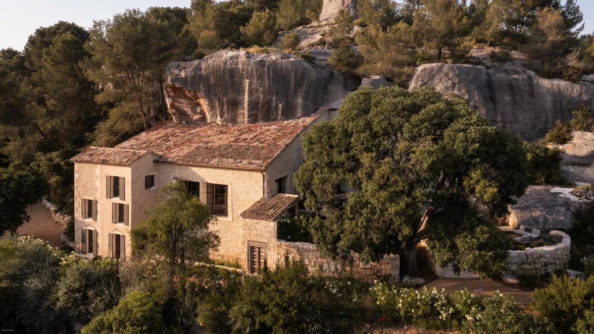 Stone villa set among cypress and olive trees amid soaring limestone rock formations, forested hillside
