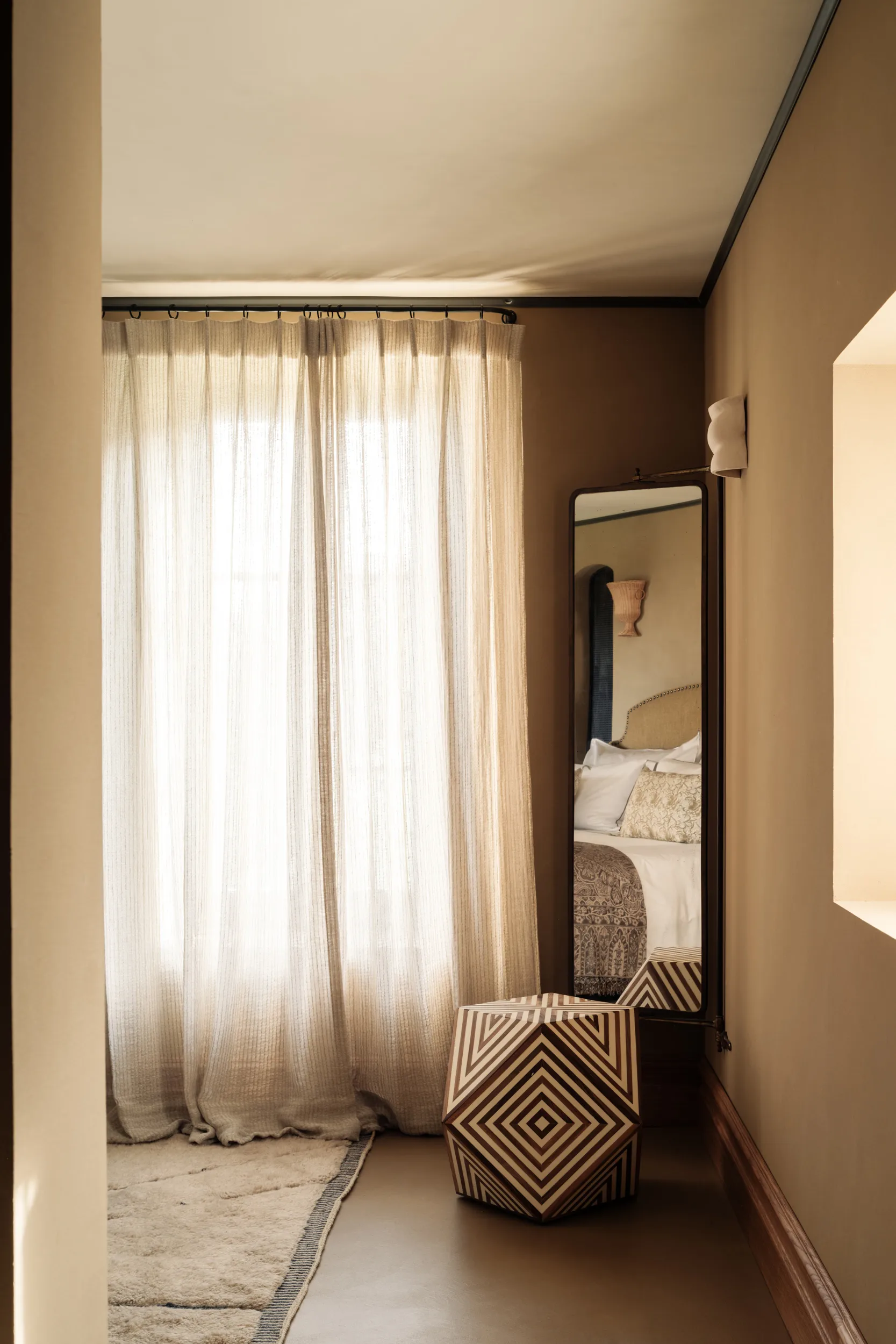 Narrow dressing hallway with sheer linen curtains, tall mirror, geometric-woven seating bench