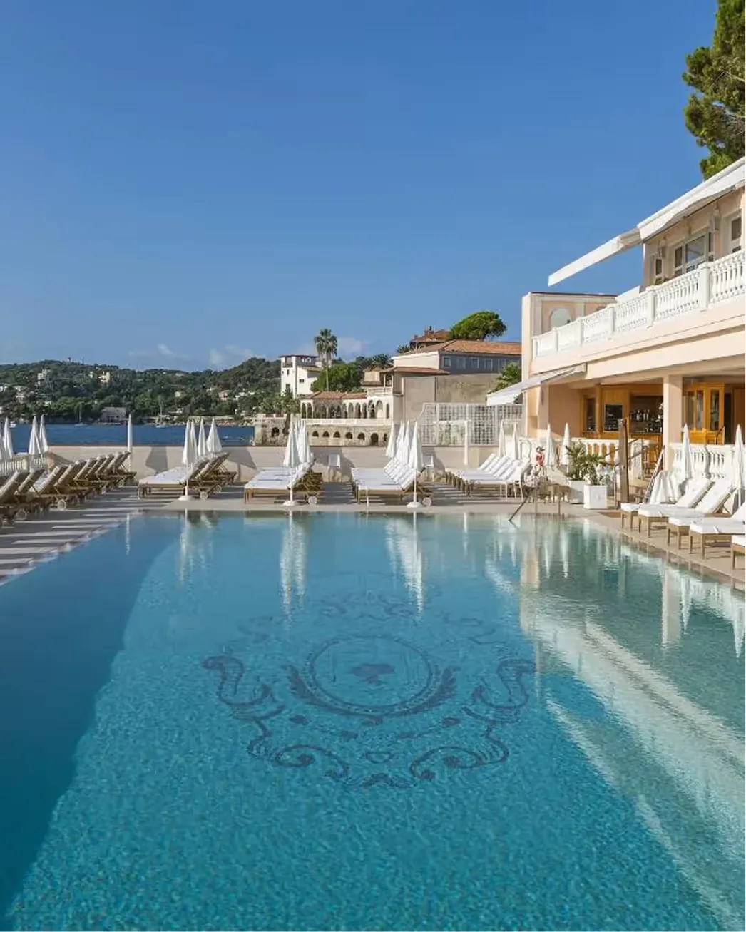 Hotel facade and pool with balustrade railings above the Mediterranean Sea