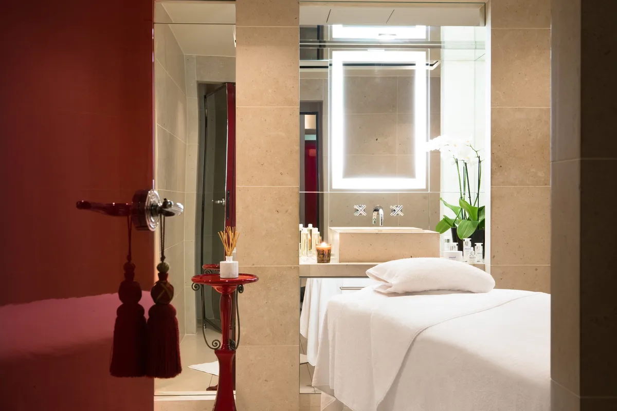 A spa treatment room with deep red accents and a massage table with white linens
