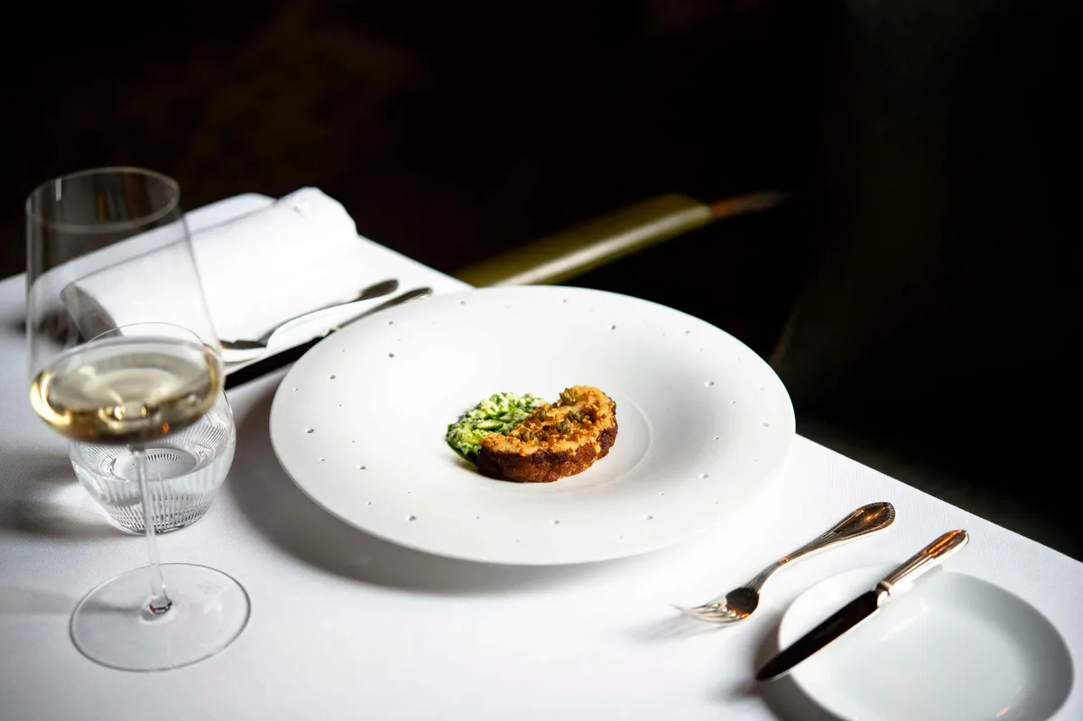 A fine dining plate with wine glass and formal place setting