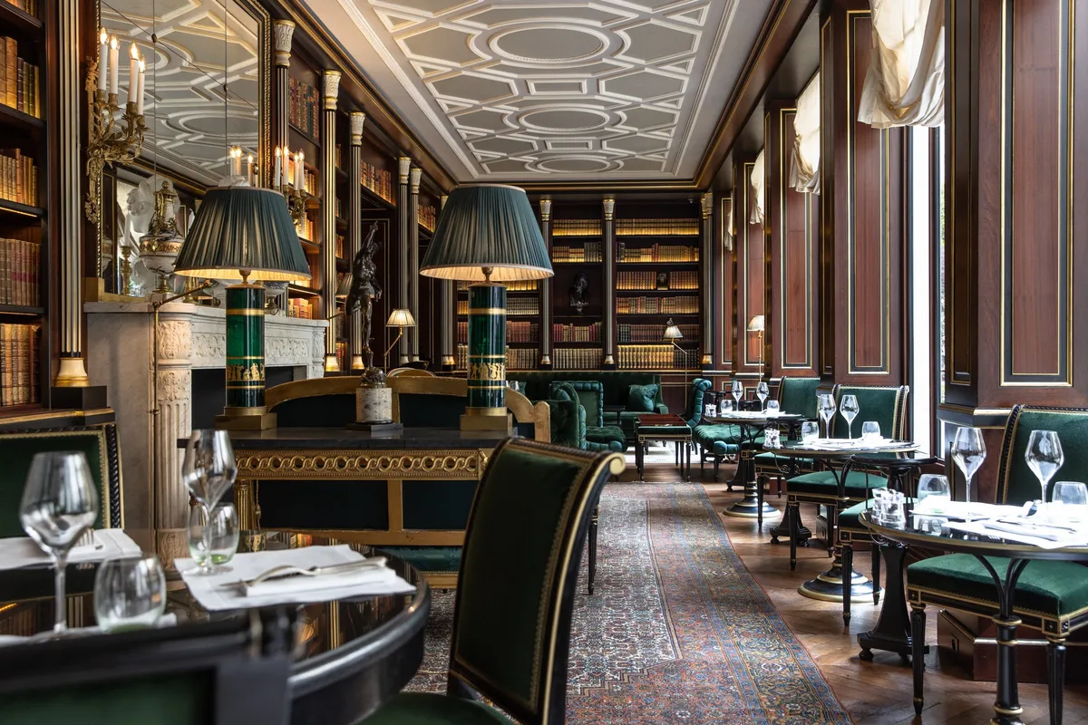 The dining room with black leather banquettes, gilded paneling, and jewel-toned furnishings