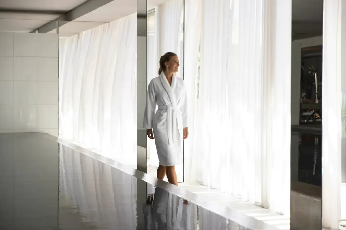 Spa therapist in white uniform in bright spa treatment corridor