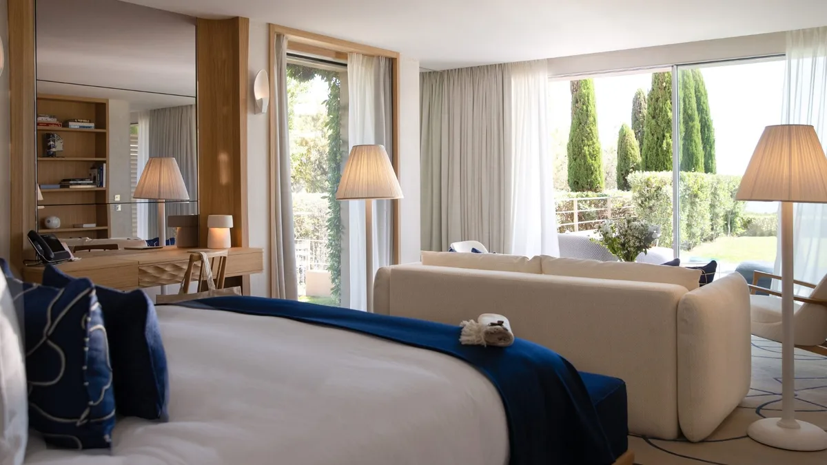 Bedroom with blue-upholstered bed and doors opening to garden