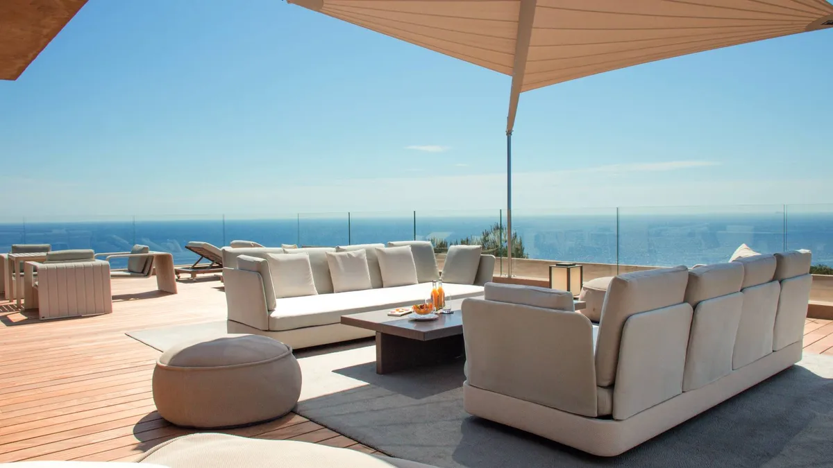Oceanside terrace with cream sofa and wooden umbrella in sunlight