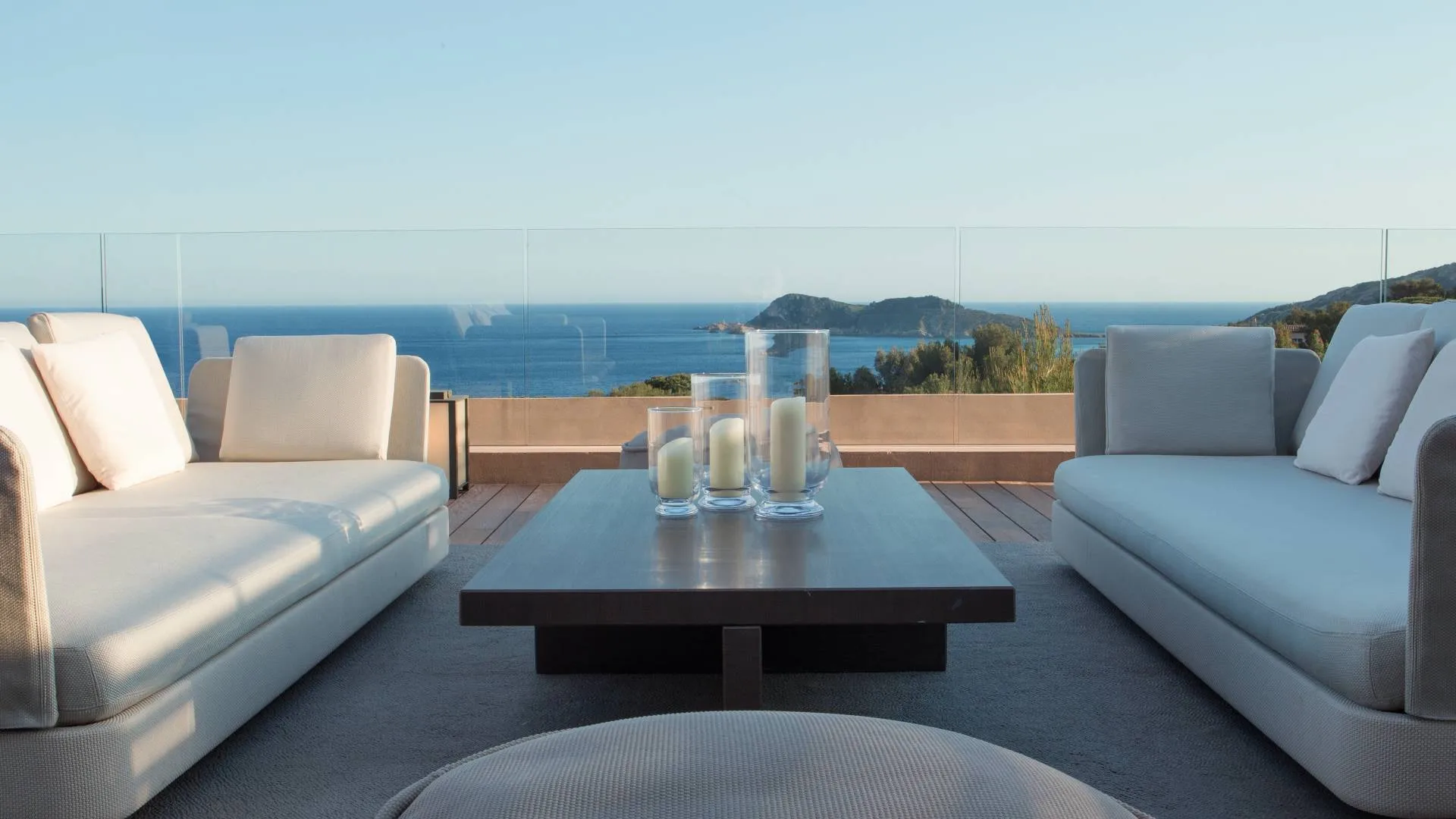 Two white lounges with gray pillows facing the sea