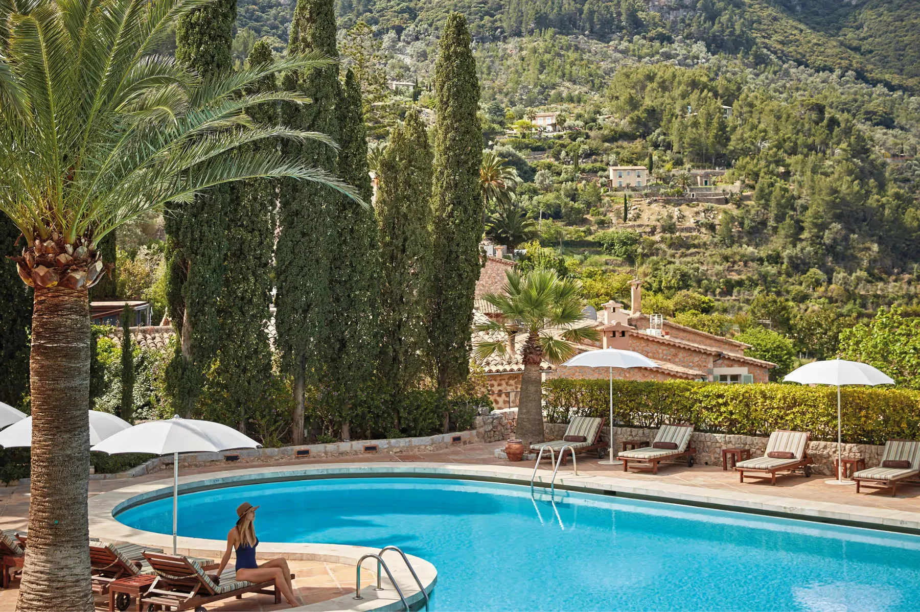 Resort pool with lounge chairs and umbrellas overlooking Mediterranean countryside