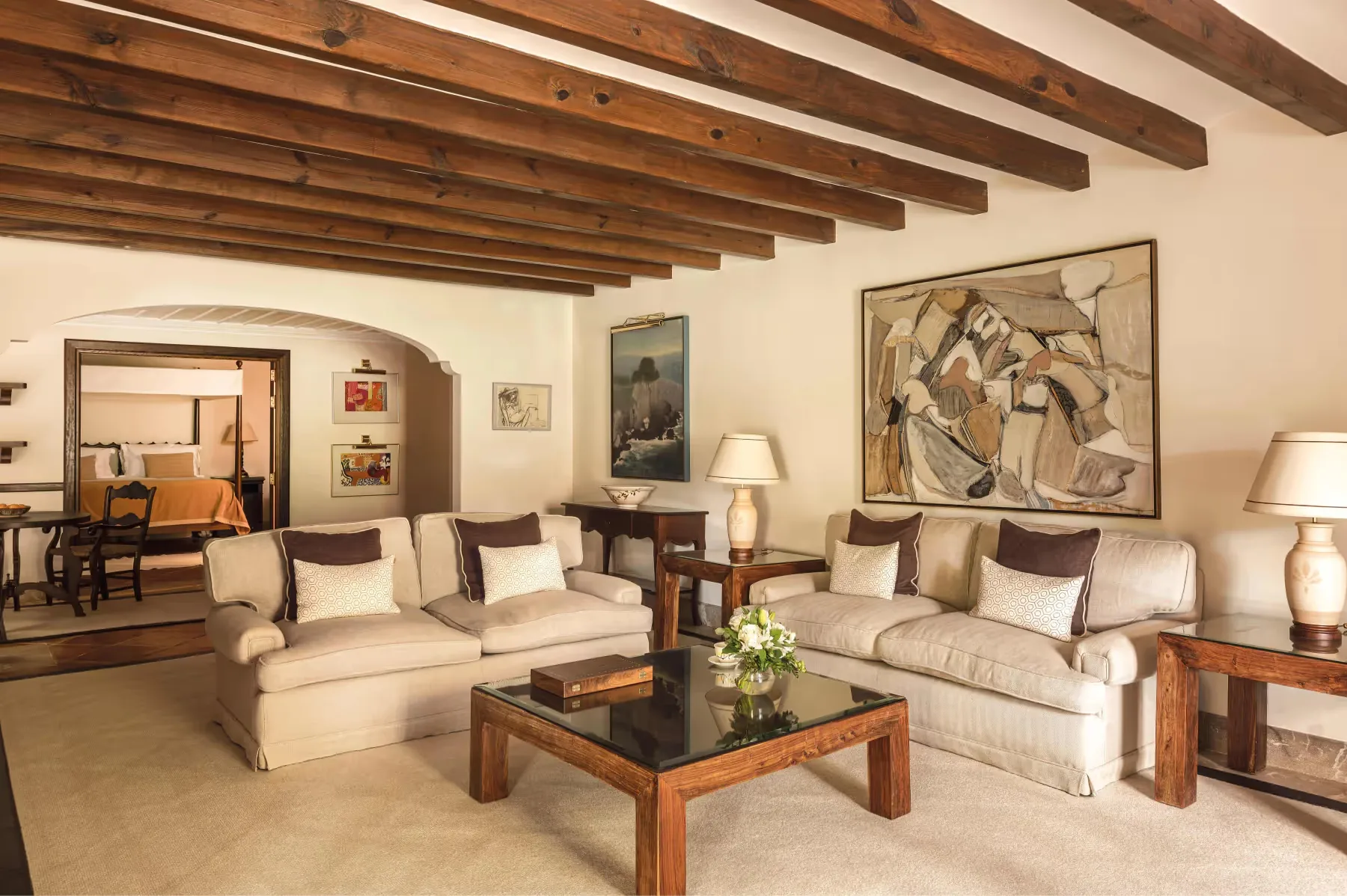 Living room suite with beamed ceiling, sectional sofa, coffee table, and terracotta tile floor