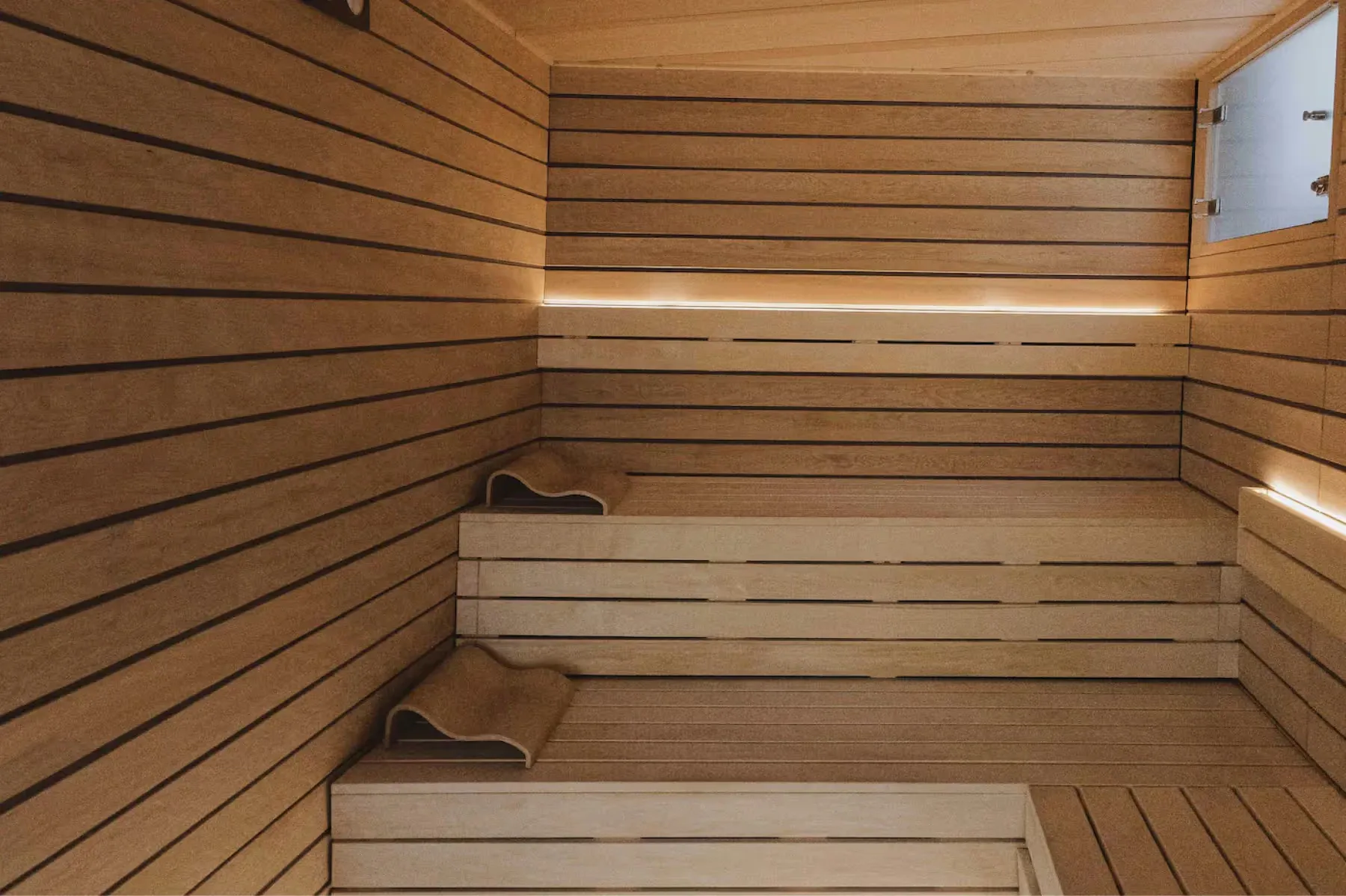 A fitness center with dark wood floors, equipment, and glass doors