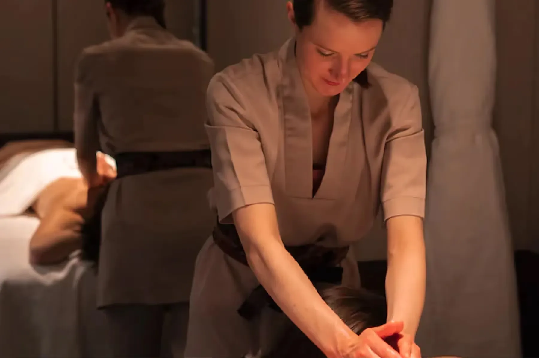 A therapist with hands on a client’s back during treatment