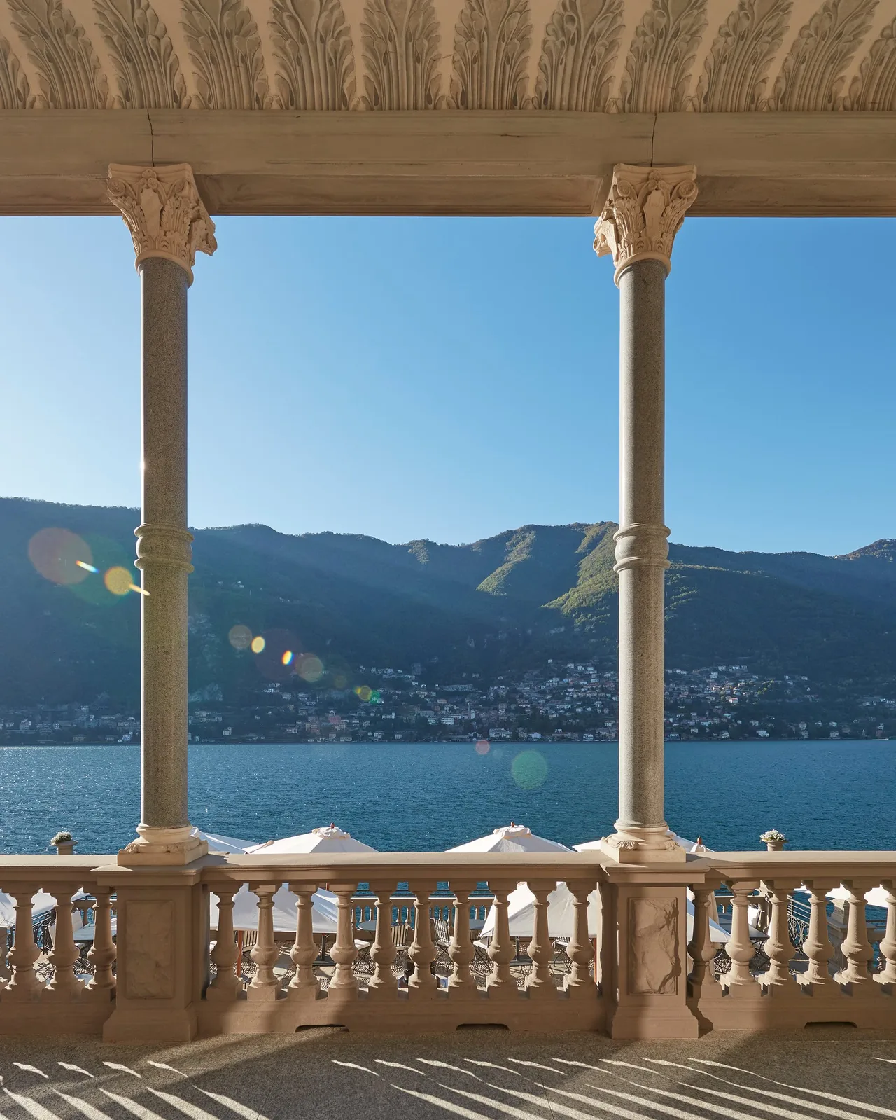 Framed view of mountains and lake from a classical colonnade with ornate ceiling details