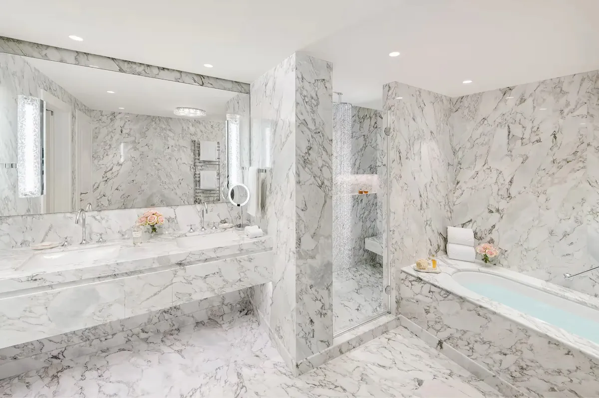 Modern bathroom with marble cladding, walk-in shower, and double vanity