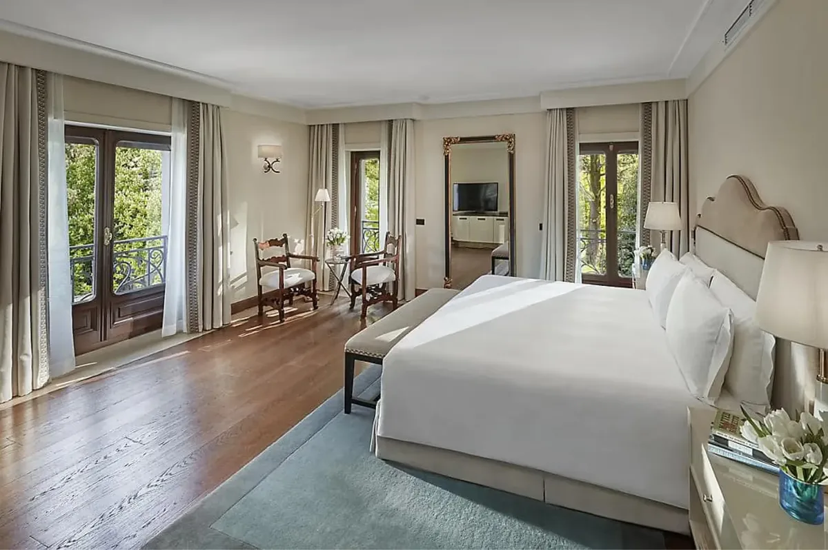 Spacious suite with multiple seating areas, wood accents, and floor-to-ceiling windows