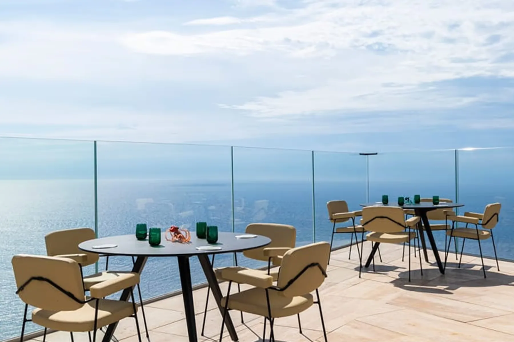 Outdoor dining with dark blue chairs overlooking the coast