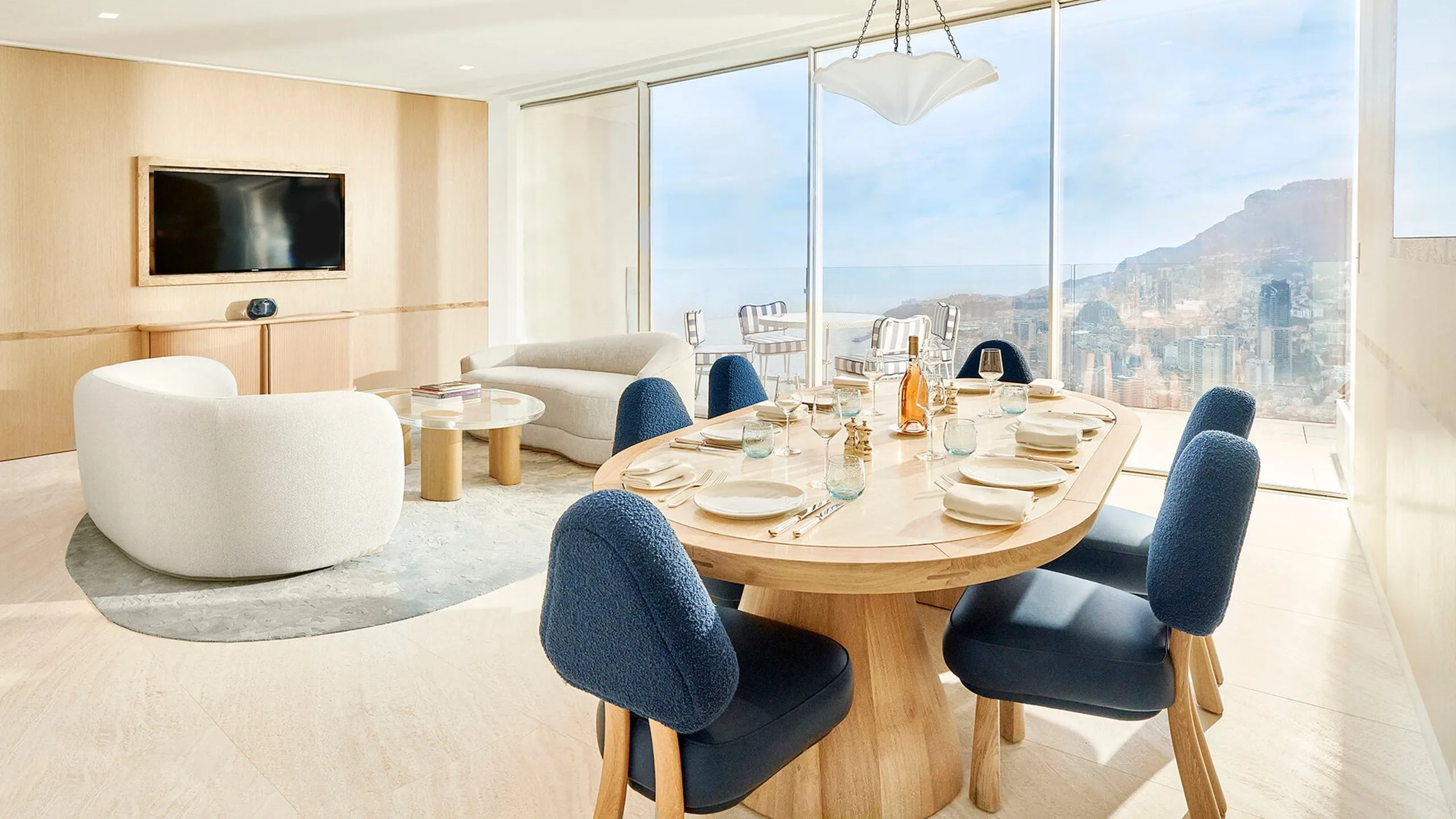 Suite with white cylindrical tub and dining area overlooking coastal landscape