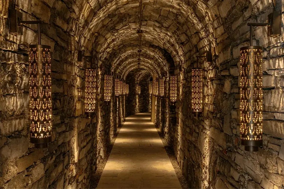 A tunnel passage with illuminated stone walls and arched brick ceiling