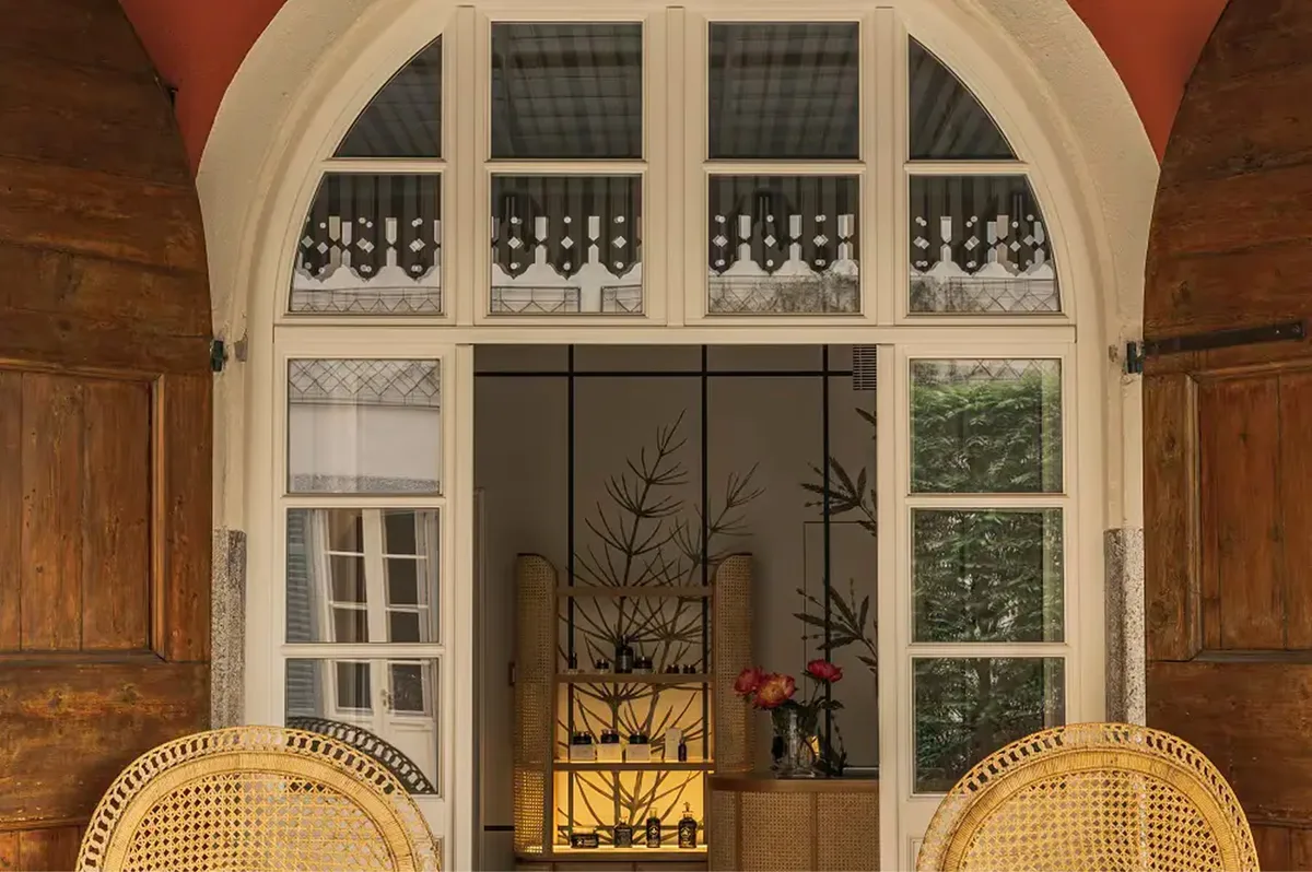 An arched glass door opening to green grounds and distant lake landscape