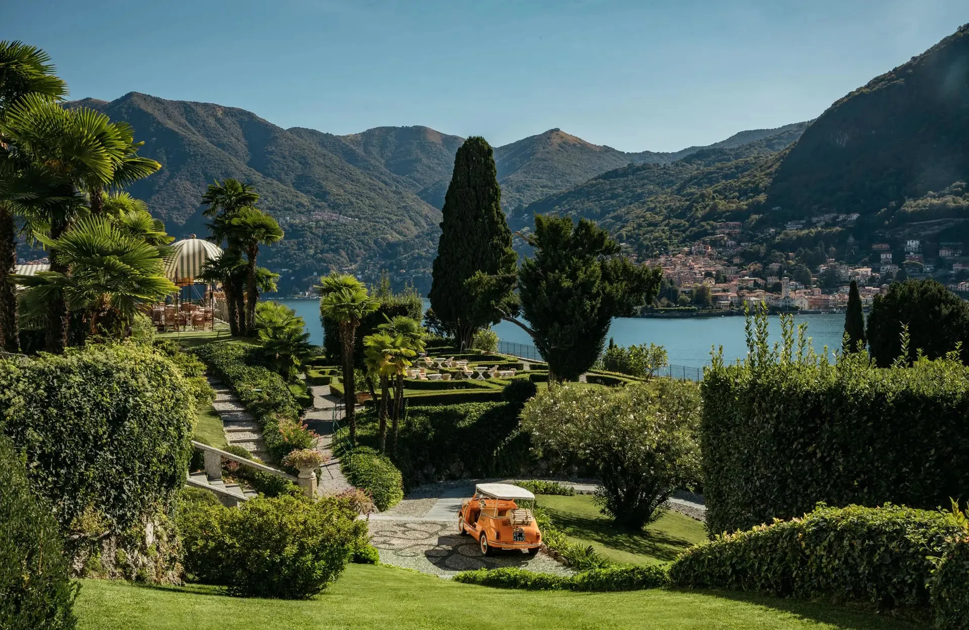 Terraced gardens with tall cypress, lawn furniture, and lake mountains in distance