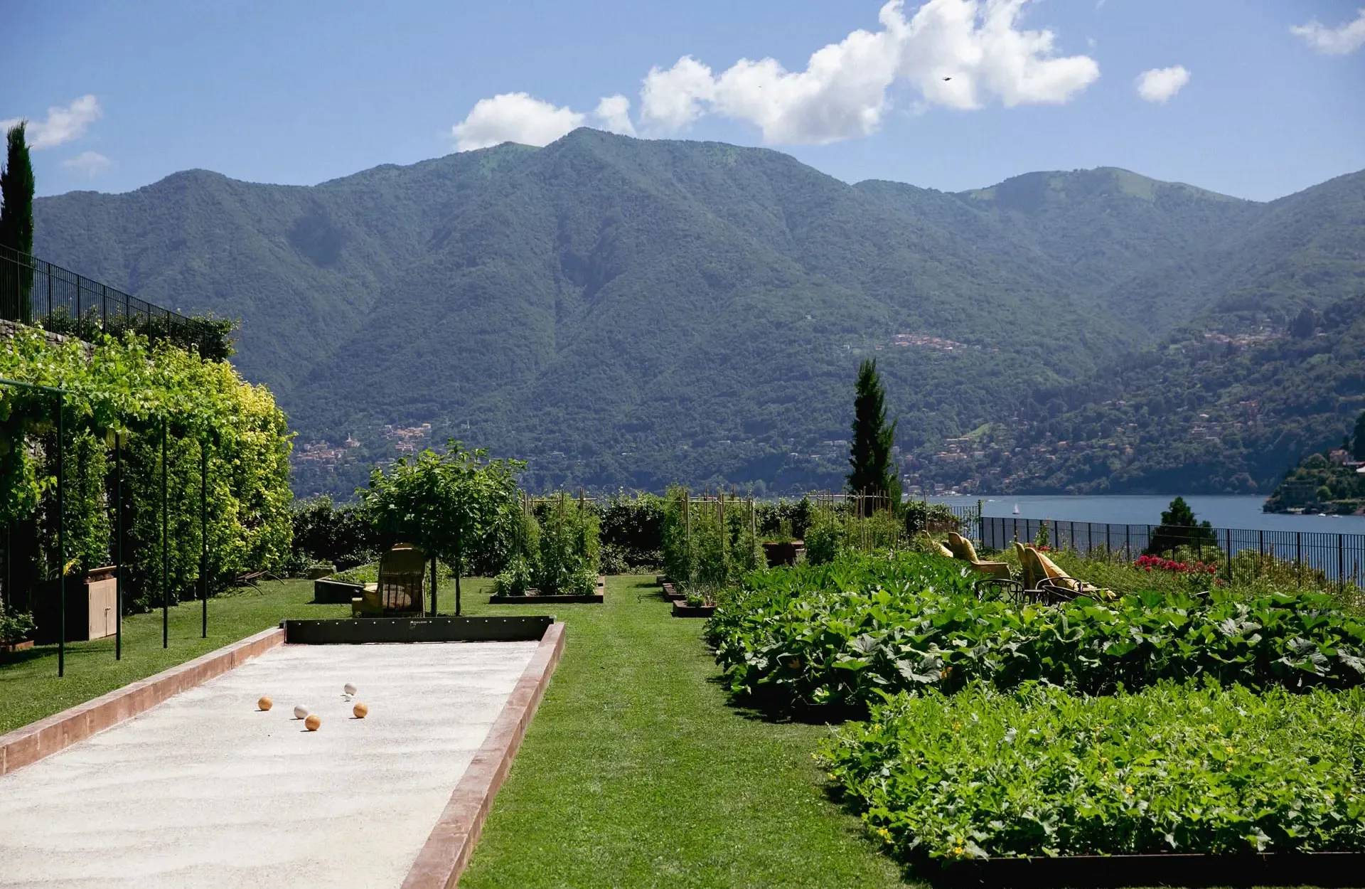 Manicured lawn with bocce court, cypress trees, and distant lake