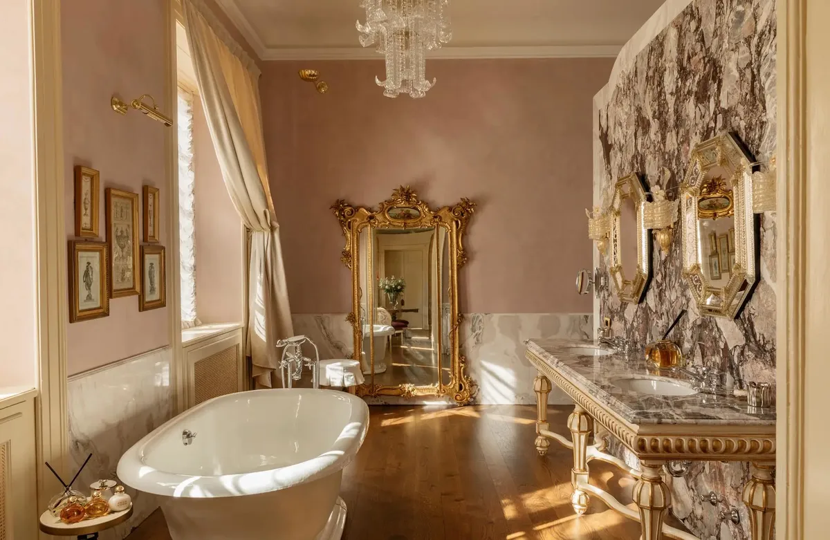 A bathroom with pink walls, freestanding soaking tub, and ornate marble details