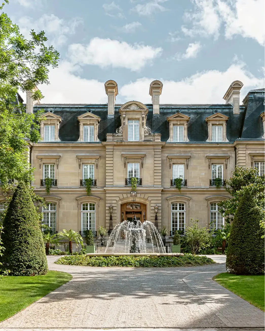 The château’s stone facade centered in frame, showcasing Mansard roofline and central entrance portal