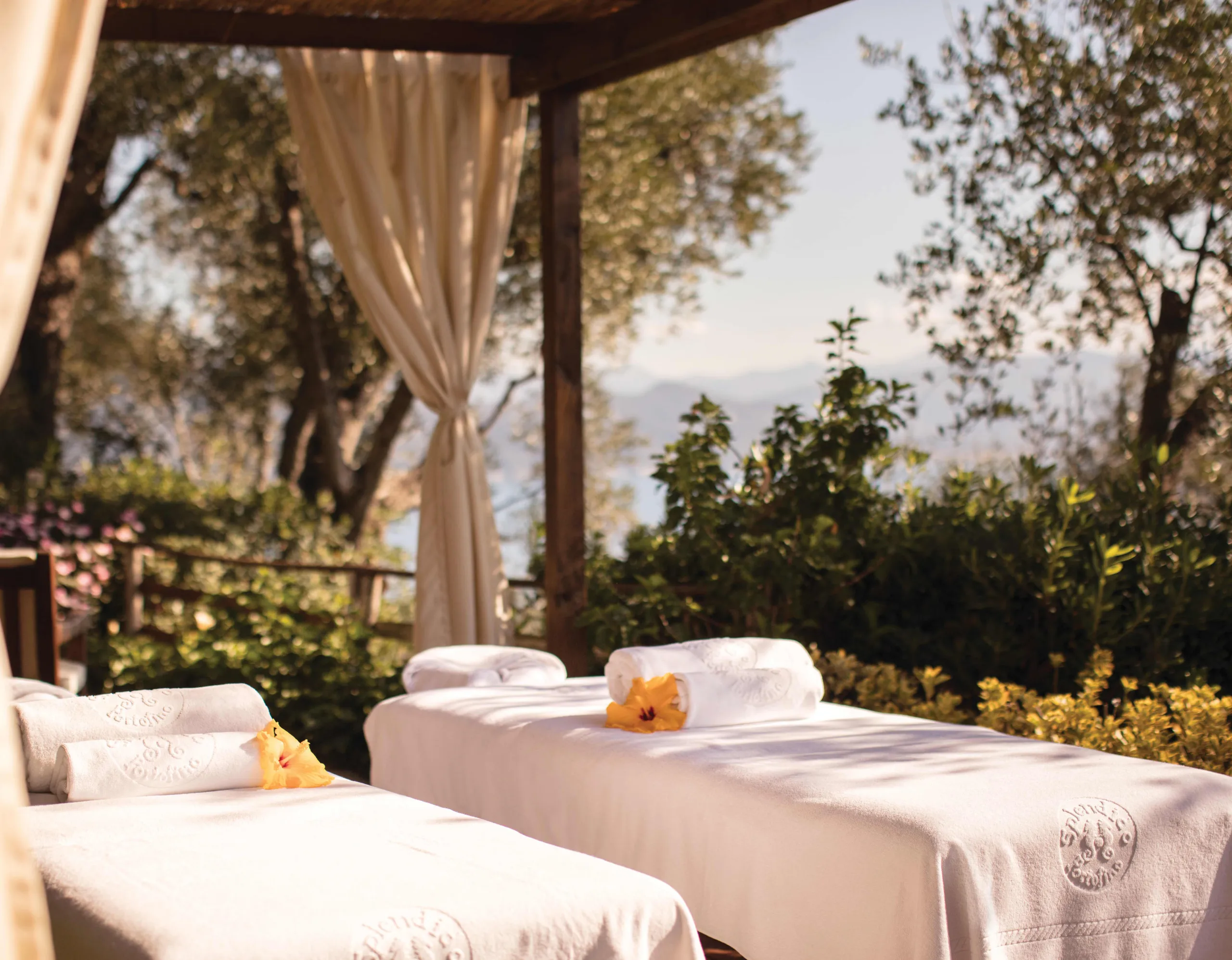 An outdoor spa area with draped cabanas and cushioned lounging platform