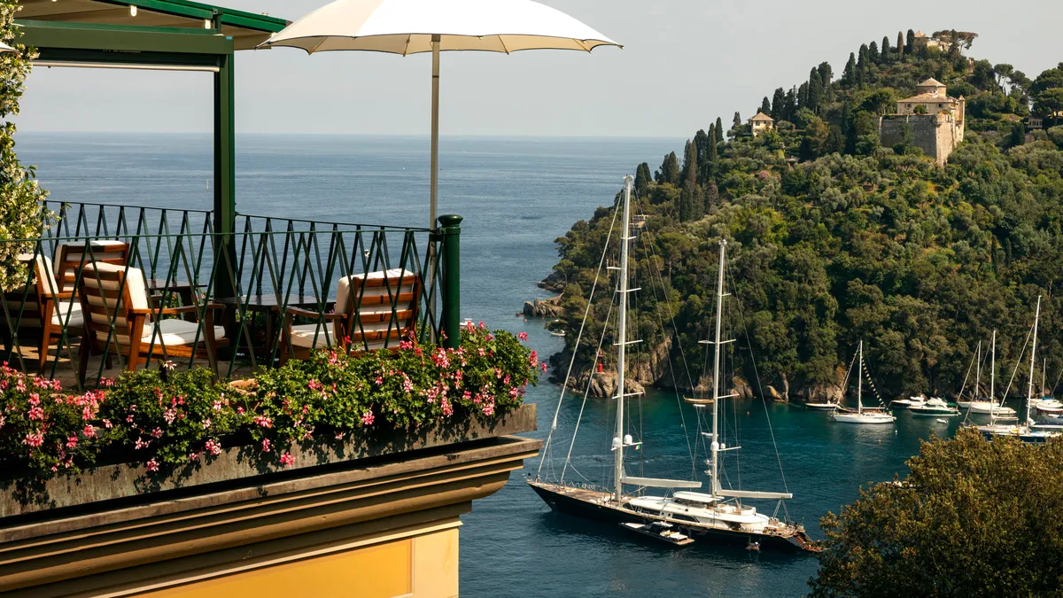 A terrace restaurant overlooking the harbor with sailboats and forested coastline