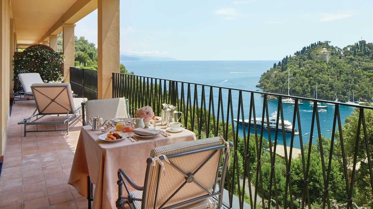 A dining table set on a terrace with sea view, framed by pergola and metal railings