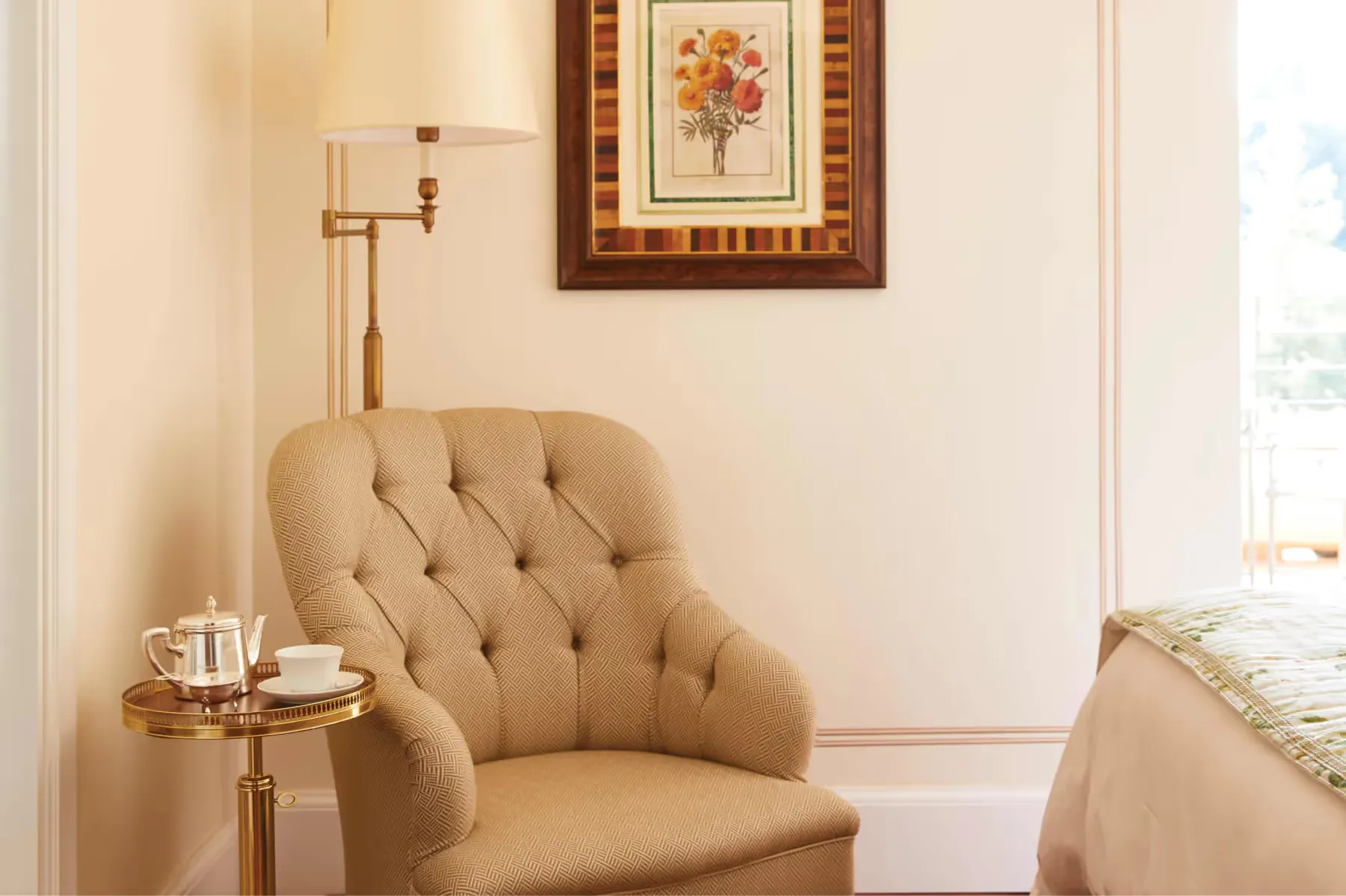 A sitting area with green velvet sofa, floral cushions, and botanical wallpaper
