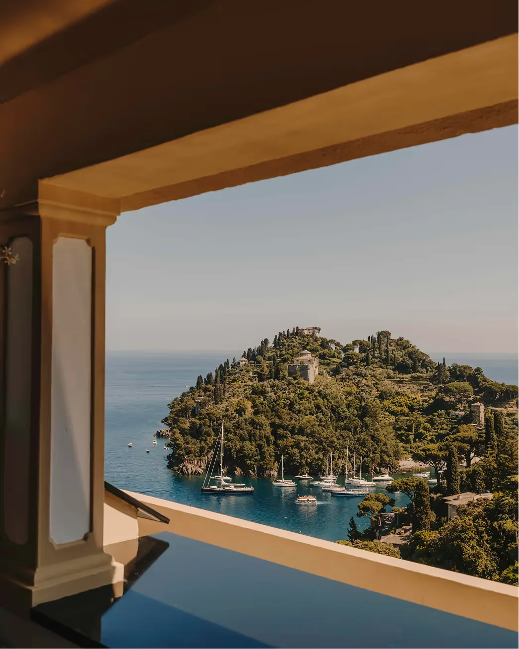 A wooden pergola framing a view of sailboats anchored in the blue Ligurian Sea