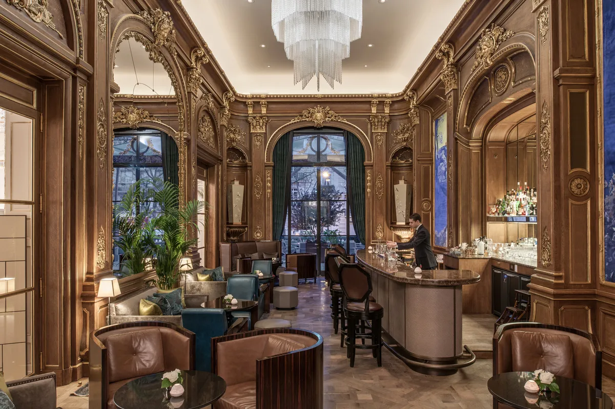 Ornate lounge with wood paneling, blue velvet seating, arched ceilings, and classical fixtures