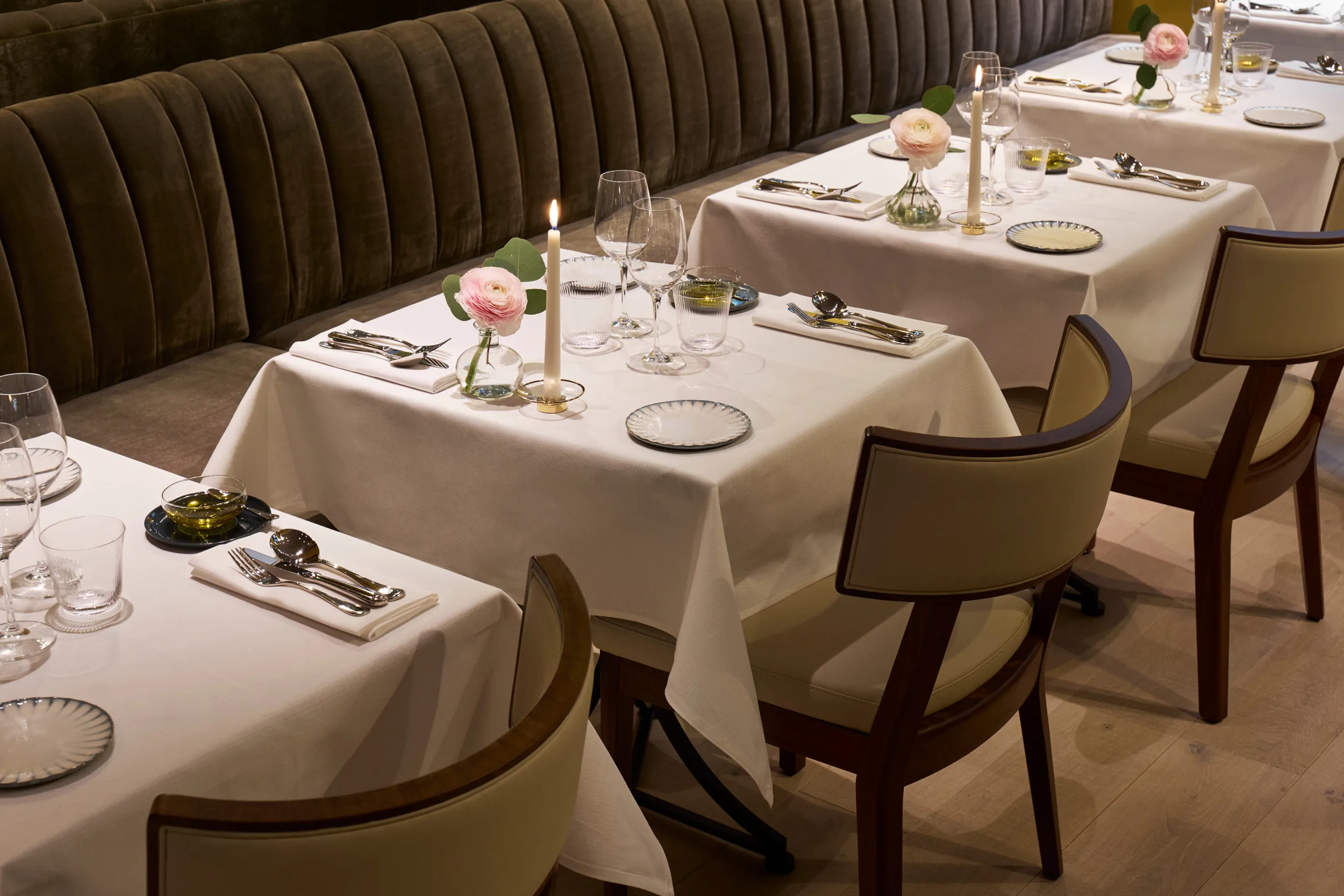 Dining room with curved banquette seating, neutral linens, and elegant table setup