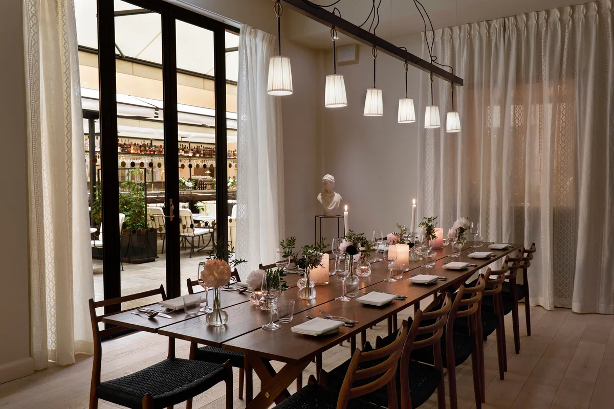 Private dining room with dark wood table, place settings, and floor-to-ceiling windows