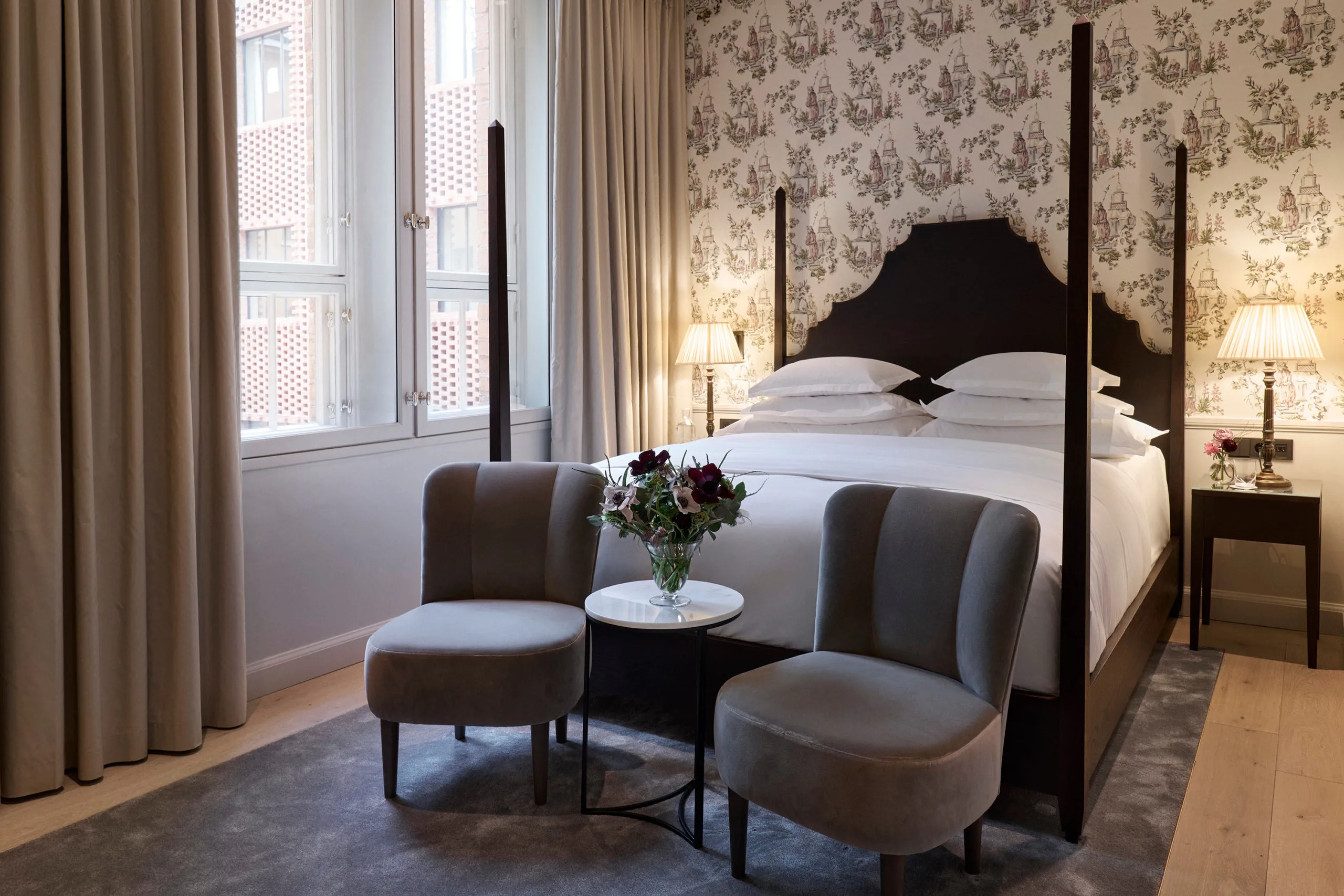Suite with patterned wallpaper, four-poster bed, and lounge seating area