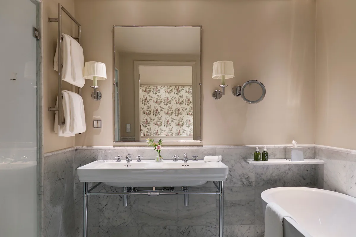 Marble bathroom with vessel sink, brass fixtures, and vintage-style mirror