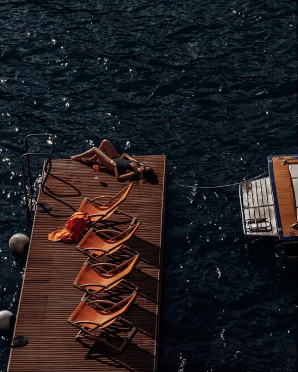 Aerial view of sunloungers arranged on a wooden deck floating on dark water